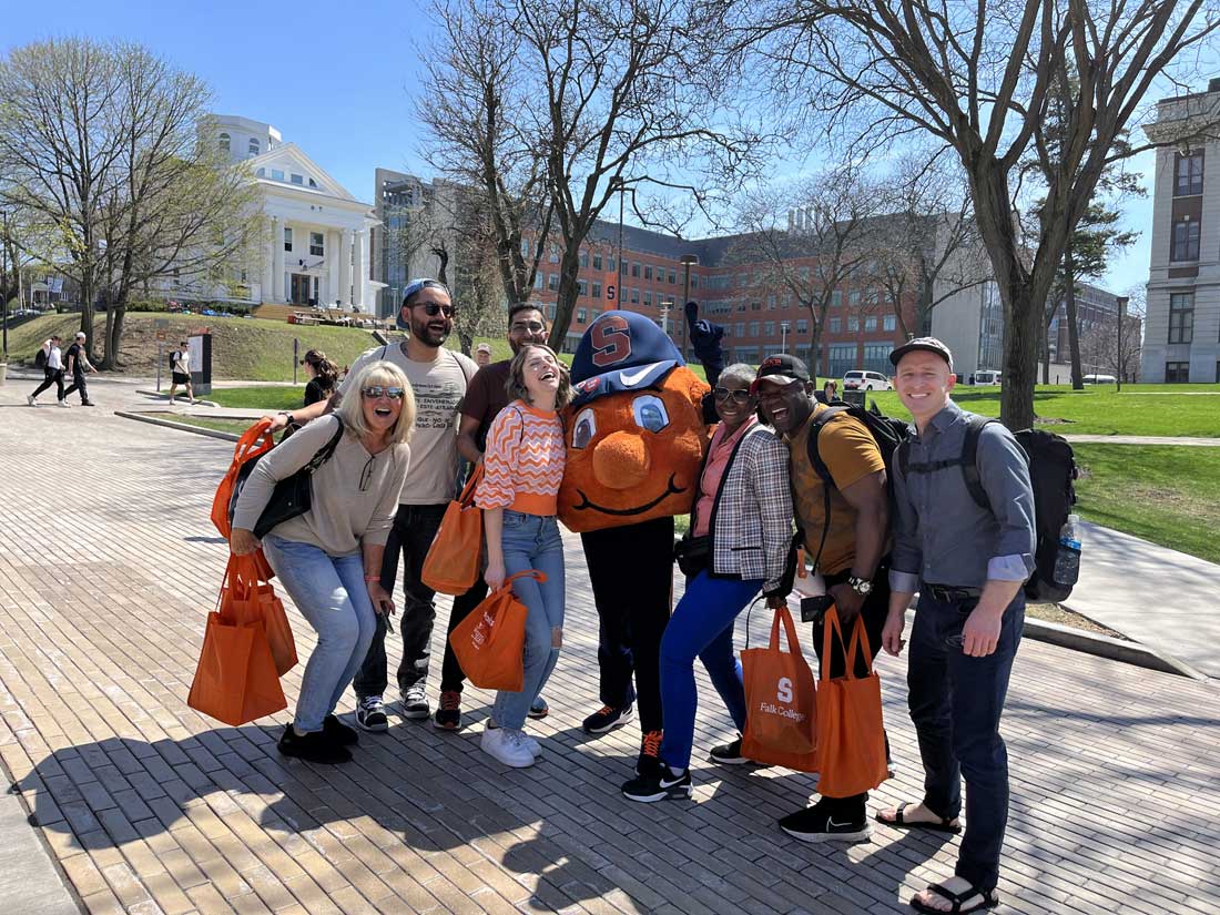 A group of individuals are posed outside on Campus