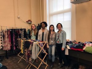4 students stand in a room full of compiled clothing