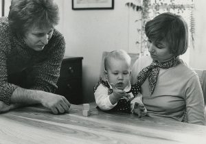 2 women sit at a table with a baby