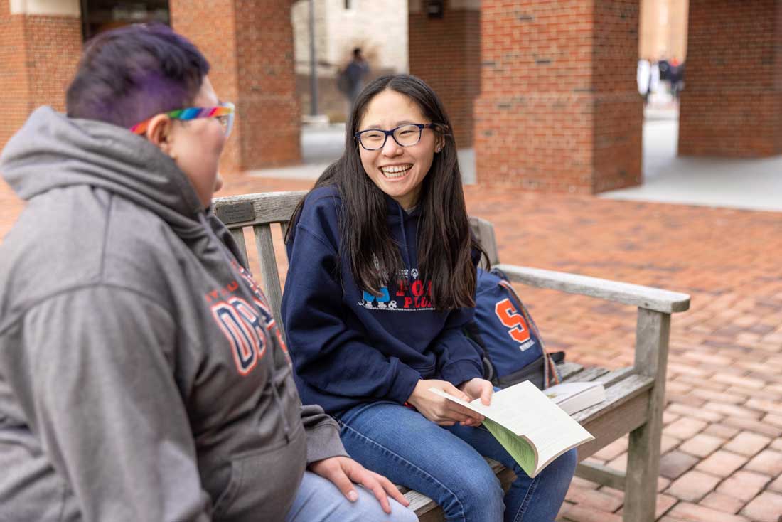 Photo of Gleason sitting on a bench, smiling at a friend.