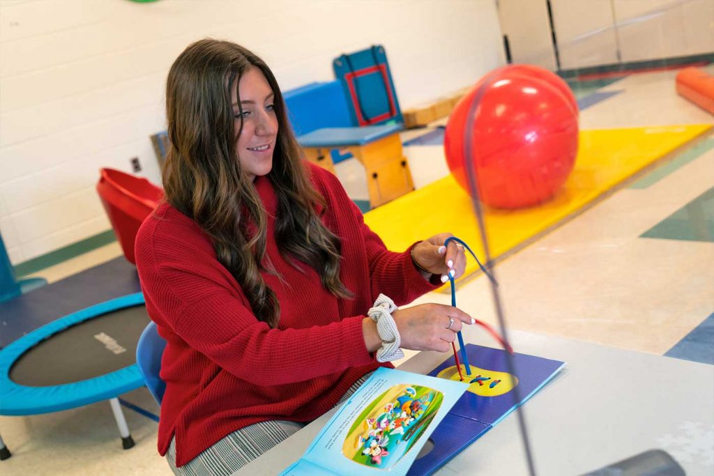 Madalyn Tallo sits at a table with a child's book