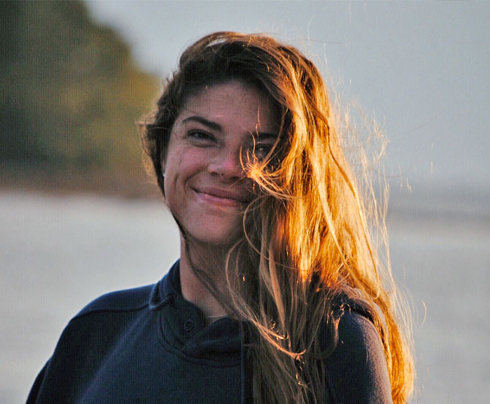 A portrait of Madison Chapin standing by the sea