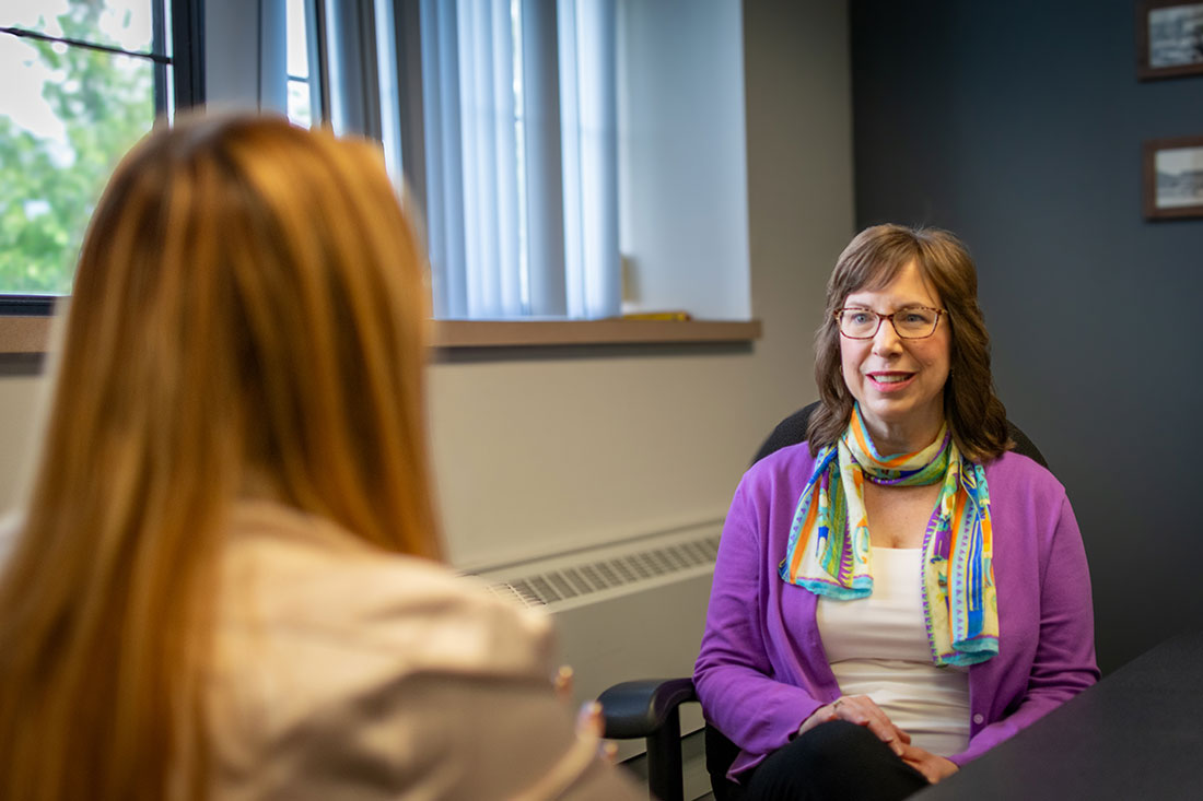 women with glasses sitting across from a women with long hair having a conversation