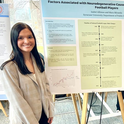 Mara stands next to a research poster