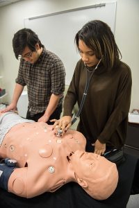 2 students work over a patient care manikin