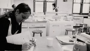 A women writes in a notebook in a kitchen environment