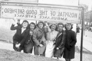 6 women students stand below a sign for the Hospital of the Good Shephard