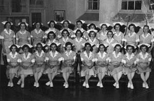 A large group of nursing students sit and stand posed in nursing outfits in 1949