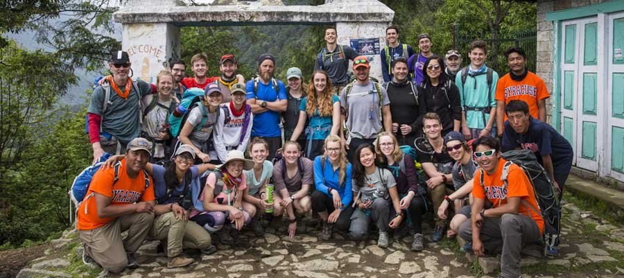 A group of students pose in a green Nepal environment