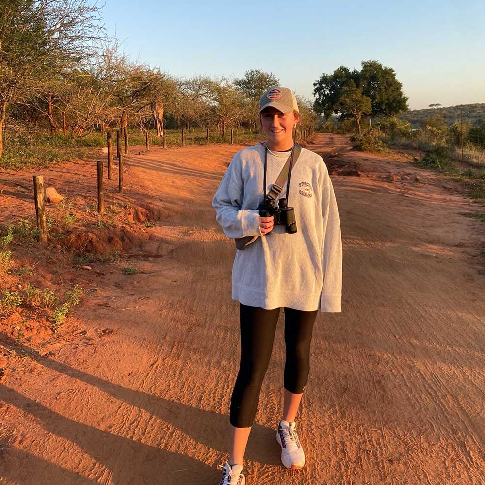 Student stands on South African dirt road