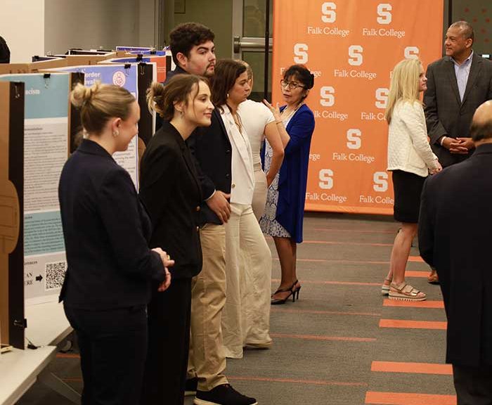Students stand by their research posters in a large room