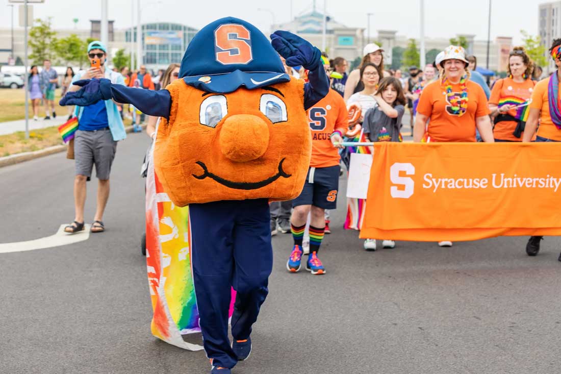 Otto and students march down a street together with an S.U. banner.