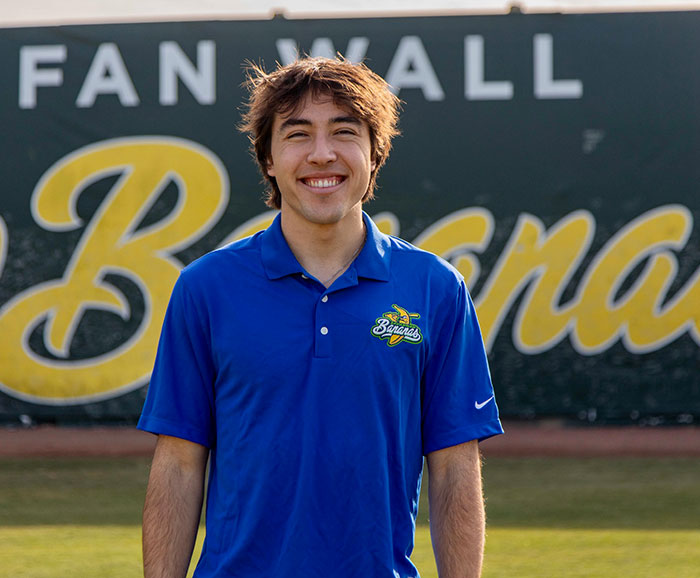 Male student wearing Bananas tshirt standing on athletic field.