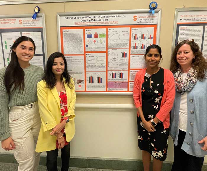 Three students and a professor stand in front of a research poster