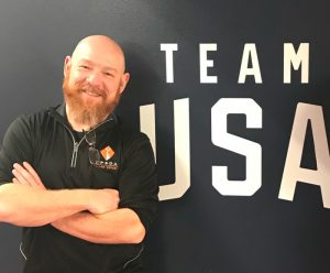 Rob Skinner stands in front of a wall decal that reads "Team USA"