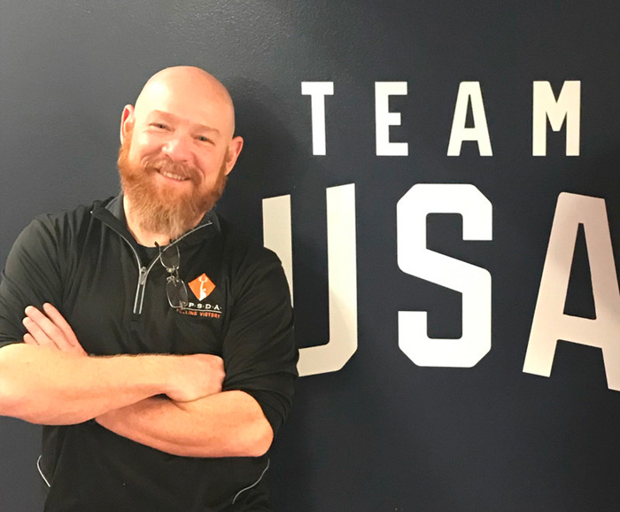 Rob Skinner stands in front of a wall decal that reads