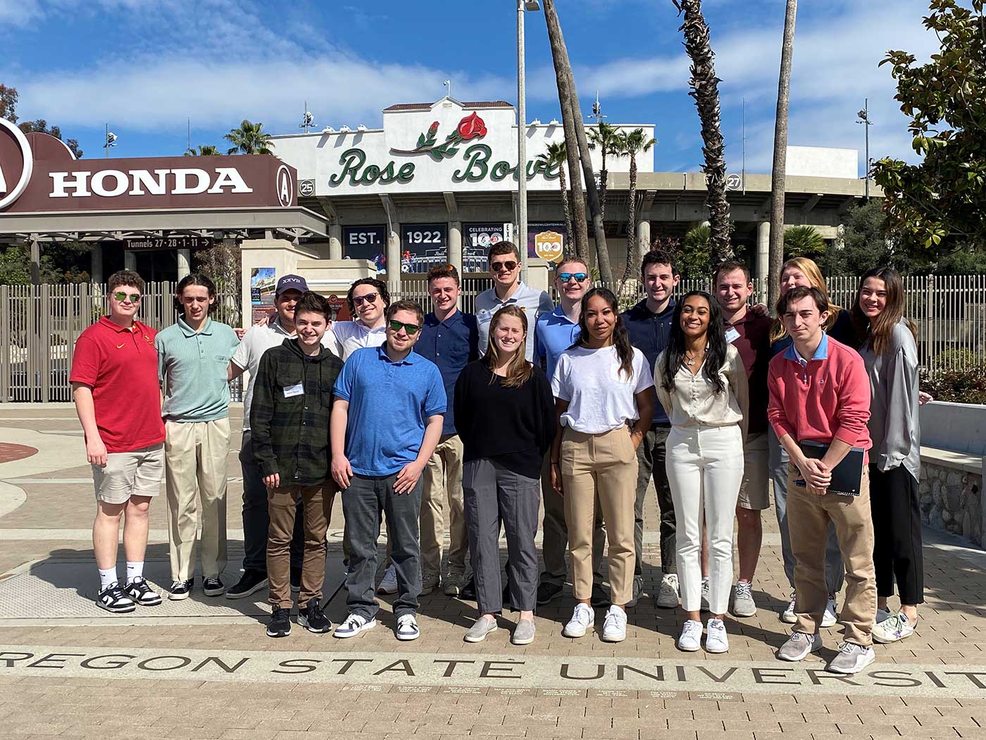 A large group is posed in front of the Rose Bowl entrance