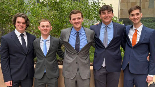 five male students members of SABR student organization , dressed in suits and standing in a line