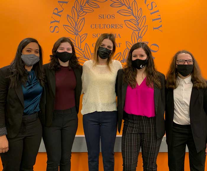 5 women in masks are posed in front of the S.U. Seal