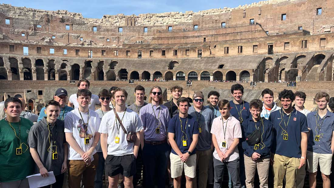 A large group of students are posed inside the colosseum.