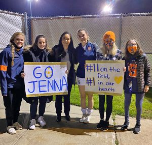 A group poses with two signs saying "Go Jenna" and "#1 in our hearts"