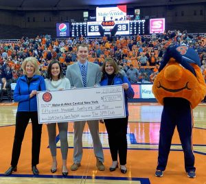A large check is held between 4 people on a basketball court