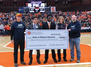 4 people hold a large check on the basketball court in the Dome