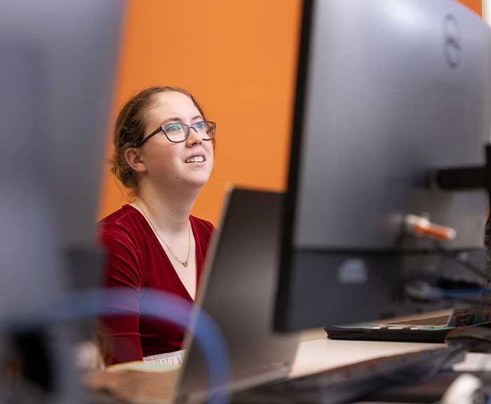 A women is seen in-between computer screens