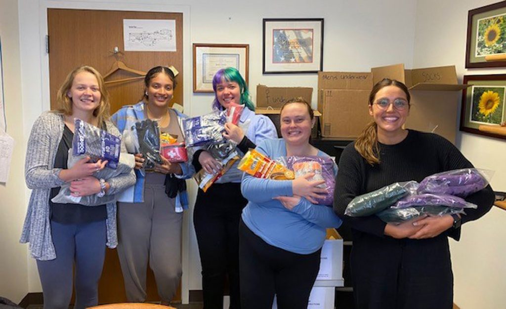 5 students pose with arms full of donation items