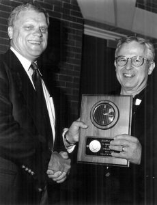 Two men hold an award plaque
