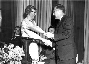 Eleanor Kenyon shakes hands with Paul Weinandy while receiving a paper