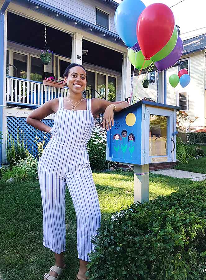 Kamya stands next to a small box in front of a house