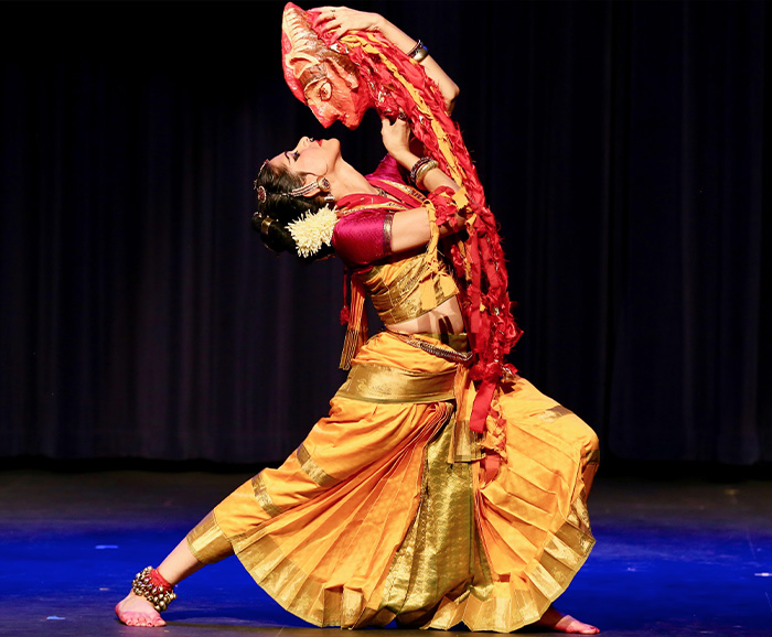 A women in an Indian dress dances with a mask