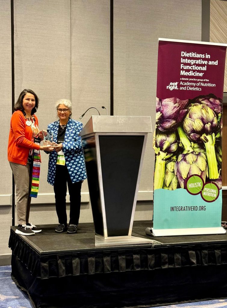 Professor Sudha Raj accepts award from Manju Karkare, registered dietitian nutritionist