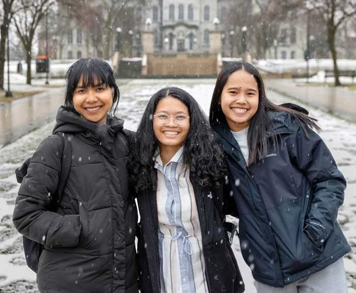 Three students pose together on snowy campus