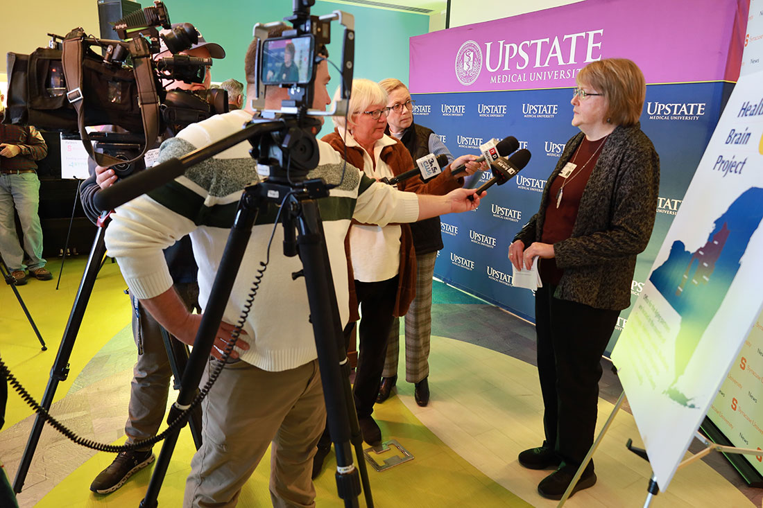 Female professor speaks on camera with reporters