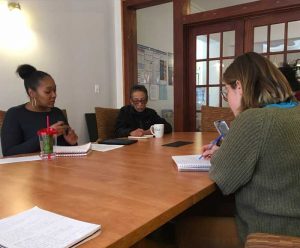 Four people sit around a table in a board room