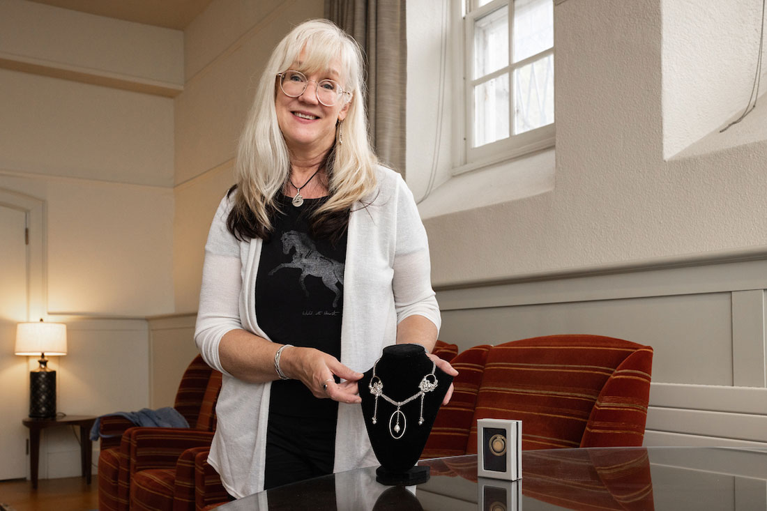 Margaret Voss stands in an office by a jewelry set