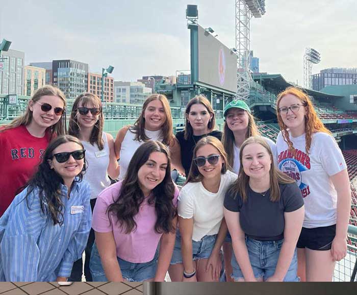 A group of female students are posed in Fenway Stadium