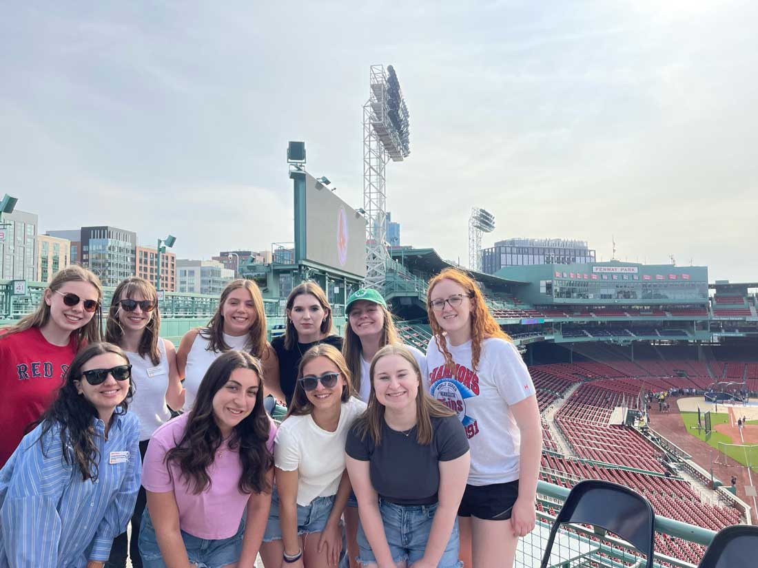 A group of female students are posed in Fenway Stadium