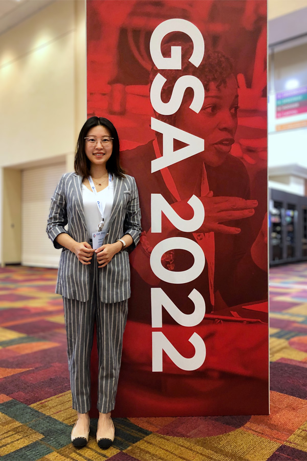 Xiaoyu Fu stands in front of a GSA 2022 banner