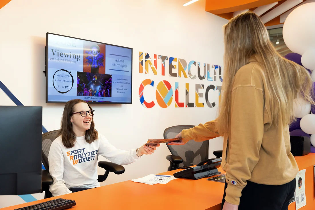 Alison Gilmore hands a paper across a desk to another girl