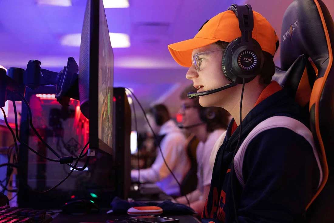 Braeden Cheverie-Leonard looks at his computer monitor while wearing a gaming headset in the esports room.