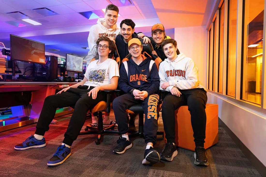Group of students sits together posing for a photo in the eSports facility