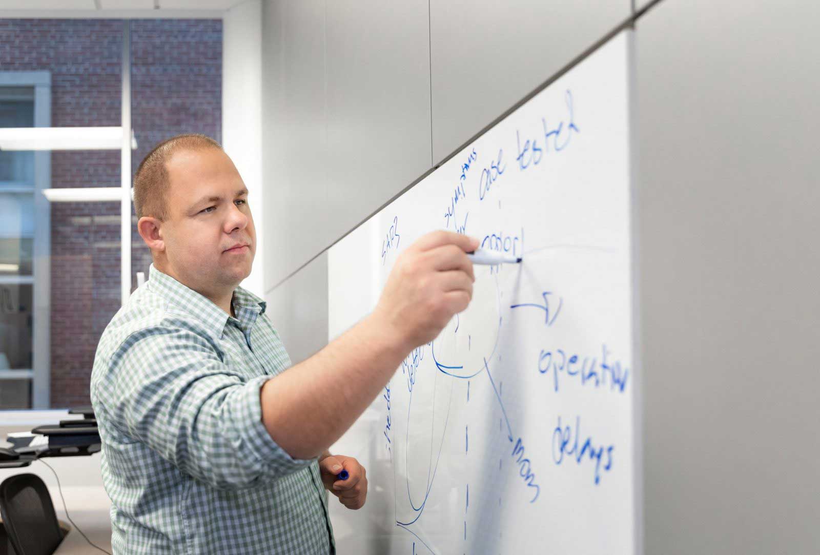 Larsen writes on a board in a classroom