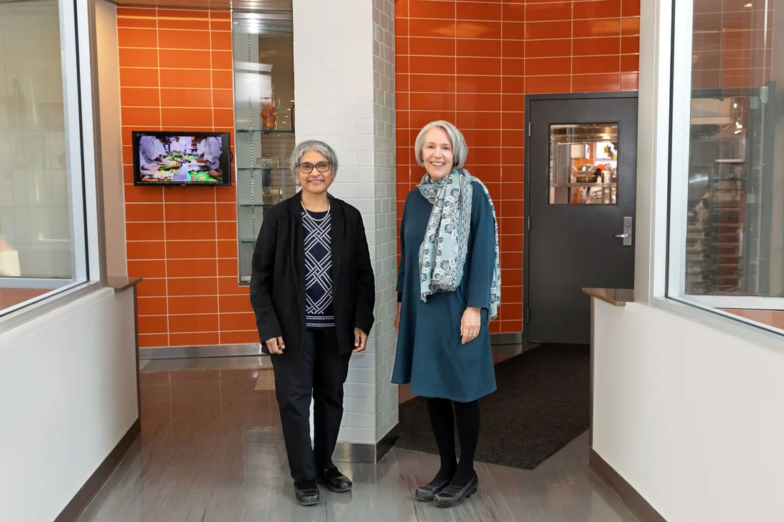 Sudha Raj and Kay S Bruening standing next to one another in a hall