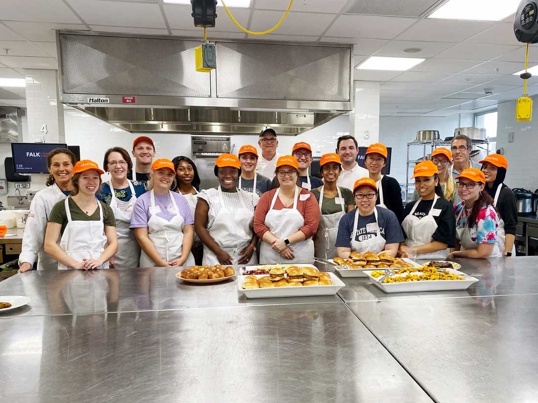 A group of students and professors posed in a commercial kitchen