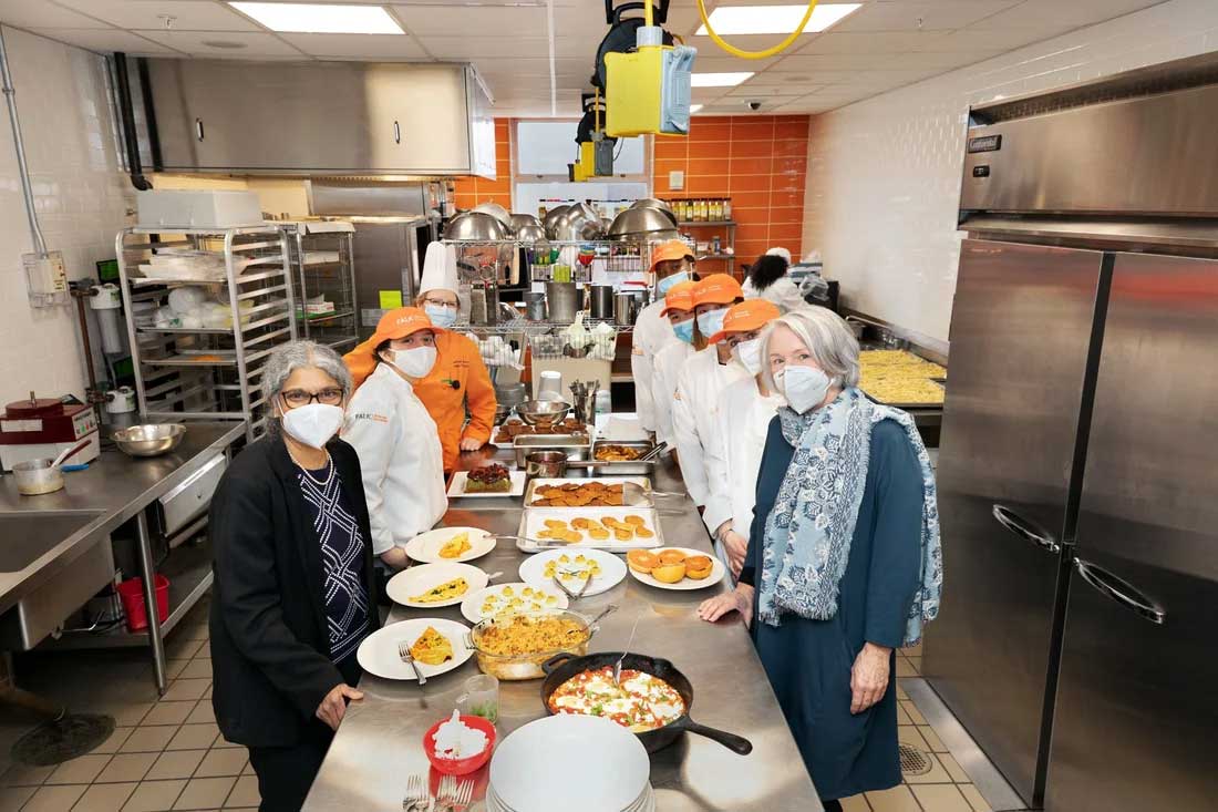 A group of students and professors are posed in a commercial kitchen