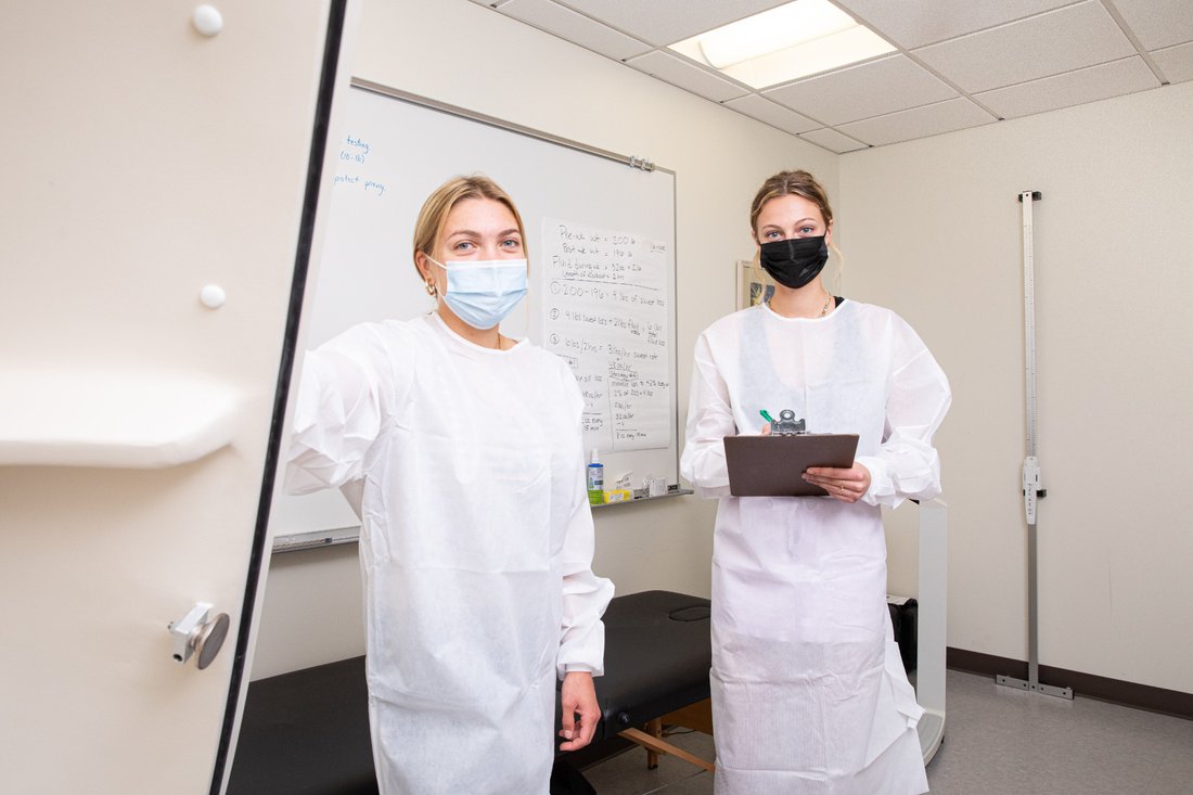 Two students standing wearing lab coats in a lab.