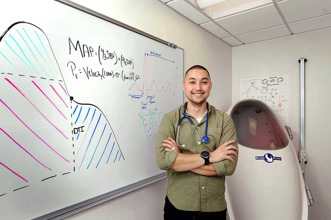 Justin Pascual stands next to a whiteboard in a lab